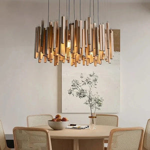 Modern chandelier hanging above a dining table with chairs in a well-lit room.
