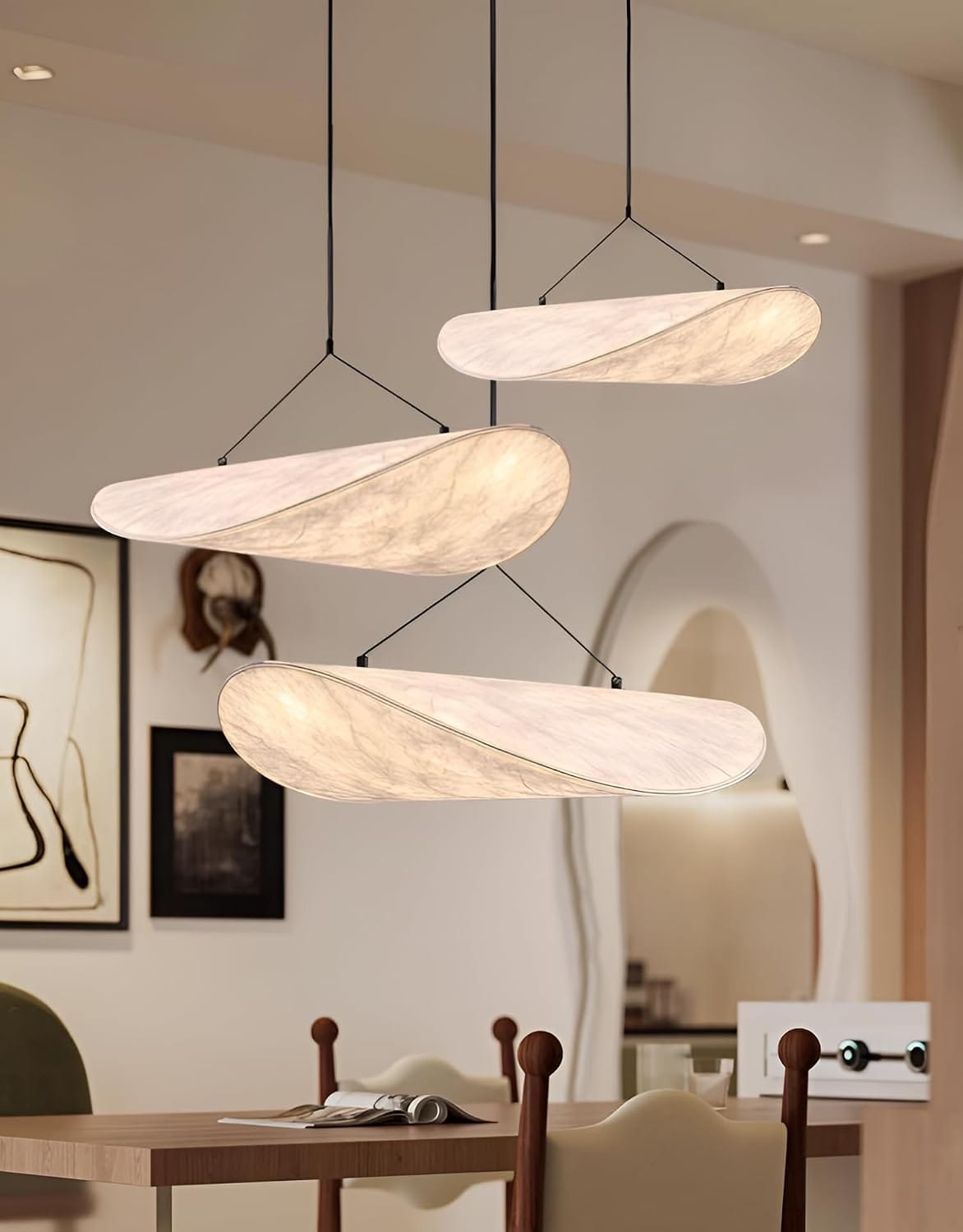 Modern pendant lights hanging in a room with a dining table and chairs.