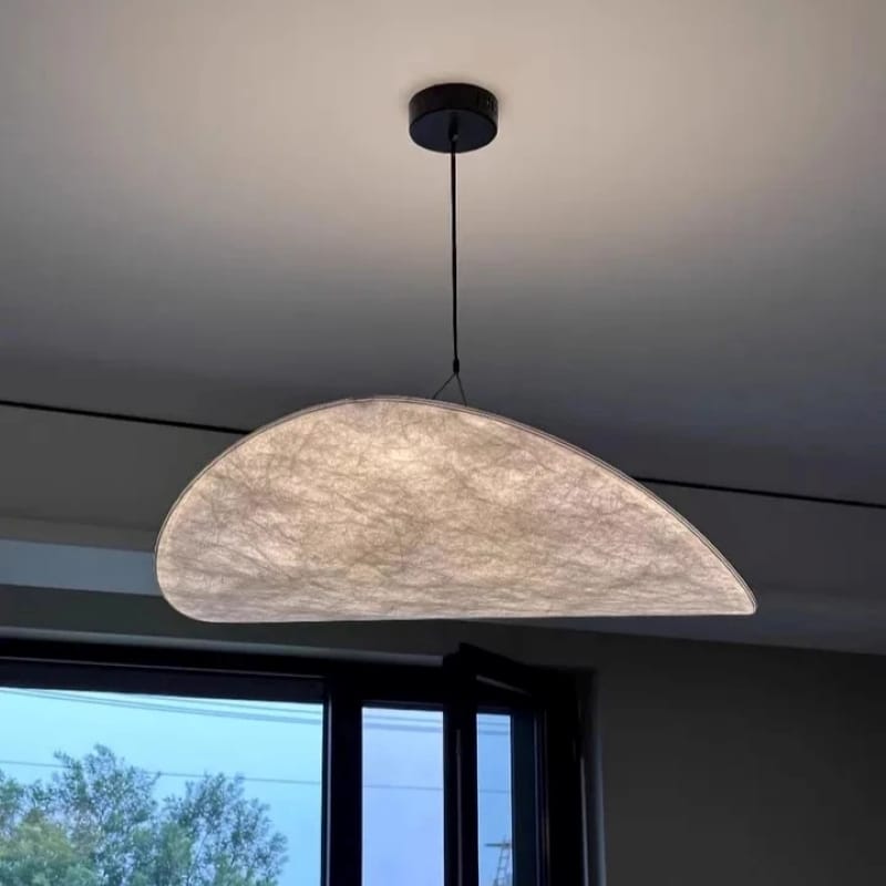 Half-moon pendant light hanging from the ceiling with a window in the background