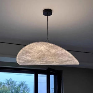 Half-moon pendant light hanging from the ceiling with a window in the background