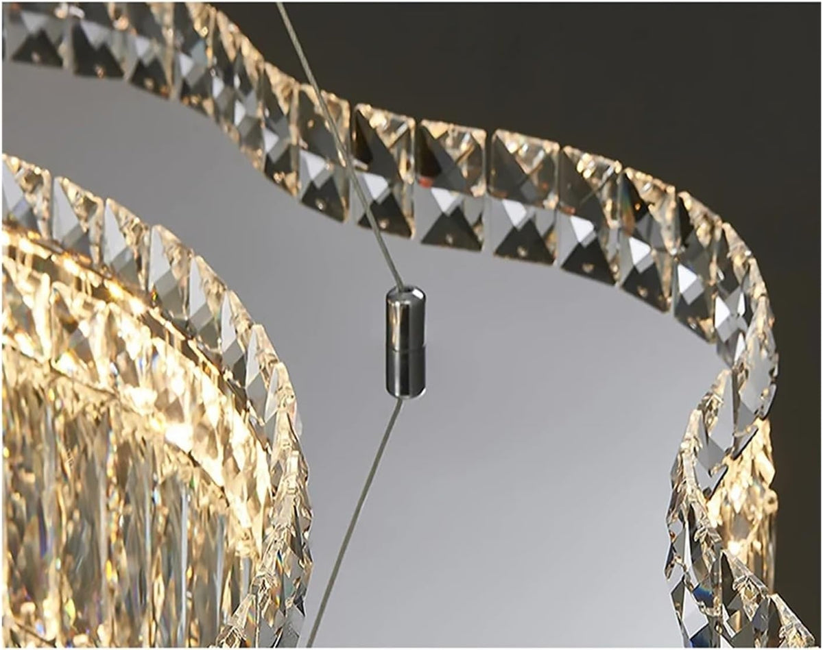 Close-up of a modern spiral chandelier with clear faceted crystal prisms and warm gold-toned lighting, suspended by thin cables with a central dark metal connector.