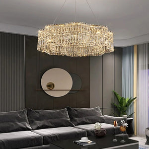 Modern living room with a large crystal chandelier, dark gray sectional sofa, and decorative items.