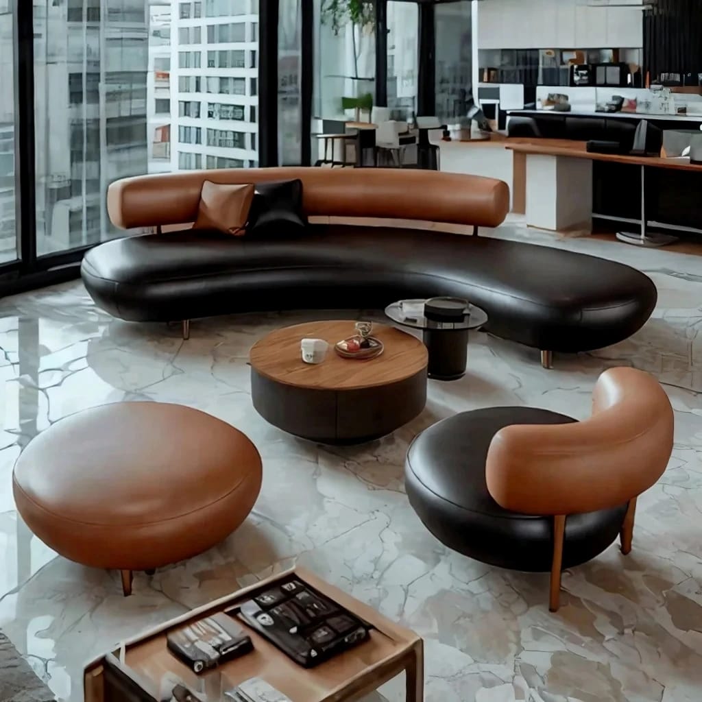 A modern curved lounge set in a bright office-like interior, featuring a black leather sofa, two tan leather ottomans, a round wood coffee table, and a matching accent chair, with large windows and marble flooring.