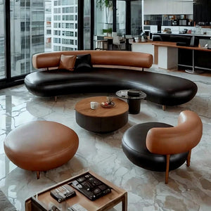 A modern curved lounge set in a bright office-like interior, featuring a black leather sofa, two tan leather ottomans, a round wood coffee table, and a matching accent chair, with large windows and marble flooring.
