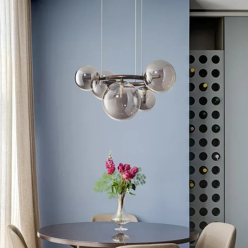 Modern chandelier hanging above a dining table with flowers in the background.