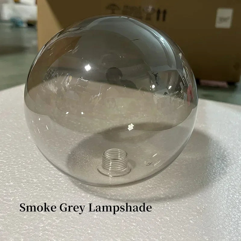 Clear smoke grey lampshade on a reflective surface with a cardboard box in the background.