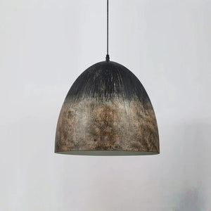 A dome-shaped pendant light with a distressed metallic finish, featuring a dark top that fades into a textured bronze and brown pattern at the bottom, suspended by a thin black cord against a light gray background.