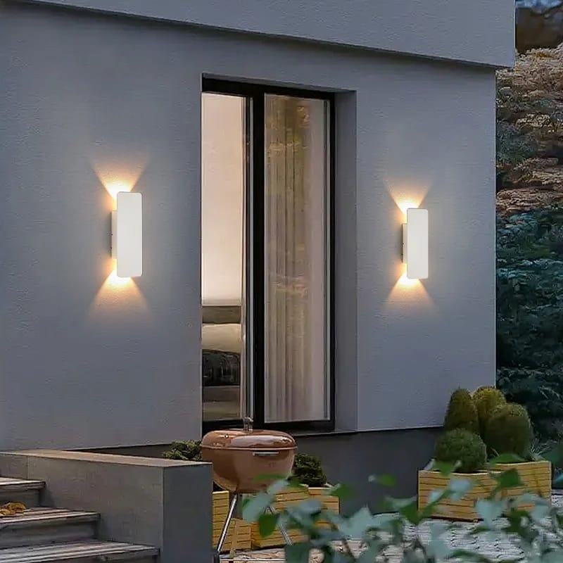 Modern outdoor wall lights on a house exterior with plants and steps.