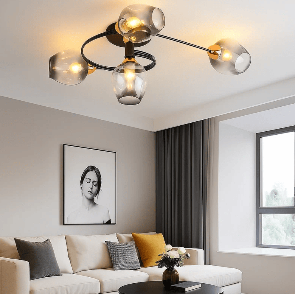 Modern multi-light ceiling fixture with four clear glass shades and a black spiral frame, mounted on a white ceiling in a contemporary living room with a beige sofa and gray curtains.
