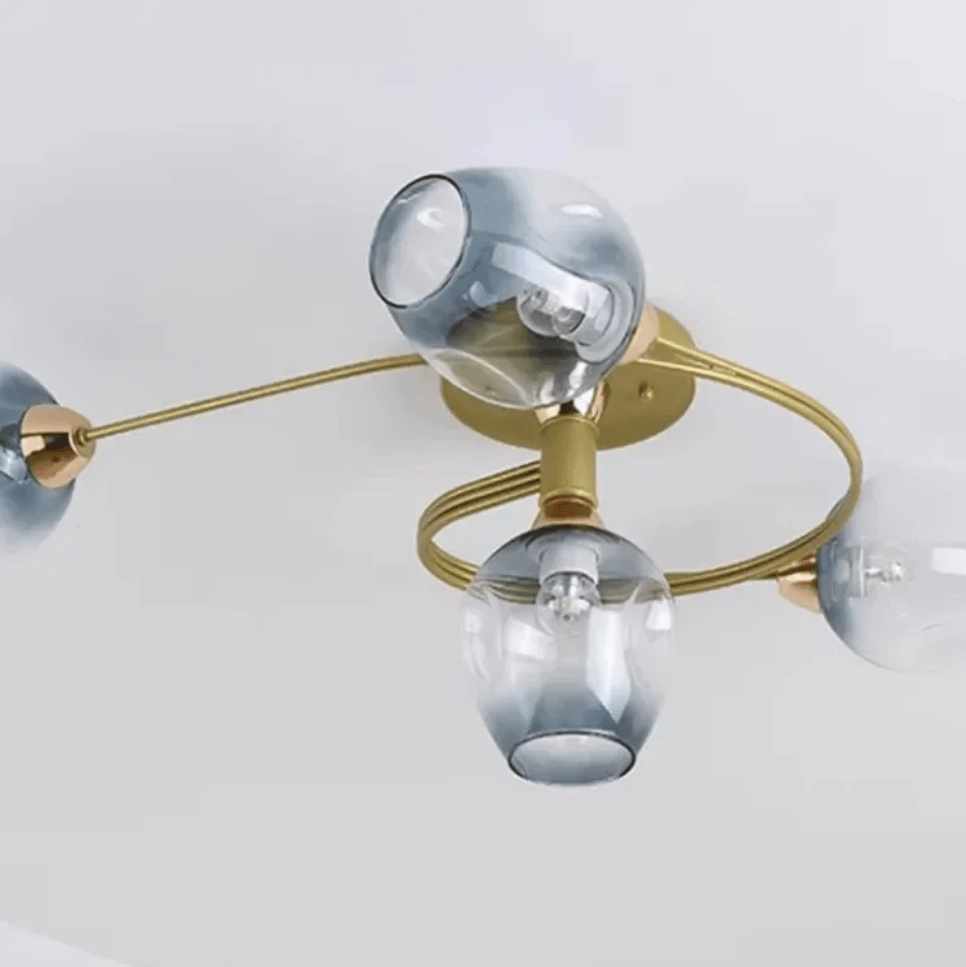 Modern ceiling light fixture with a gold-finished metal frame and three translucent smoky blue glass shades, shown mounted on a white ceiling.