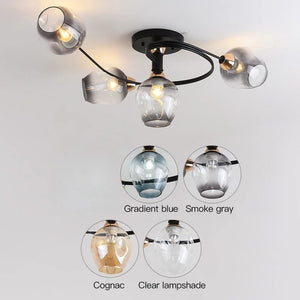 Ceiling light fixture with glass lampshades in gradient blue, smoke gray, and clear on a white background.