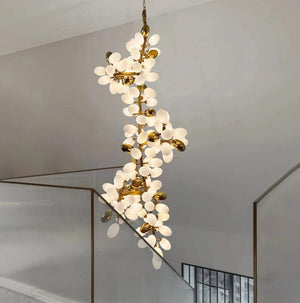A modern multi-light chandelier with white flower-shaped bulbs and gold branches, hanging in a minimalist interior setting.