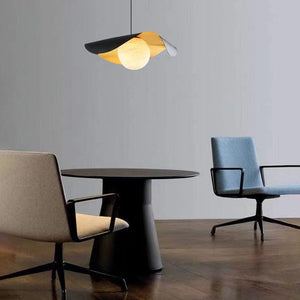 Modern dining area with a round table and chairs under a geometric pendant light.