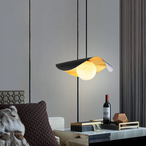 Modern pendant light fixture in a living room setting with a bottle of wine on a table.