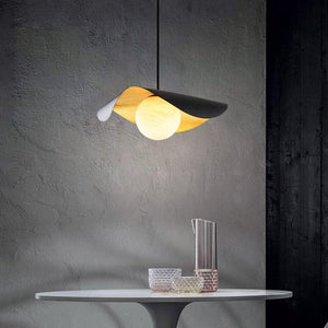 Modern pendant light with a yellow and black design hanging above a table with decorative items.