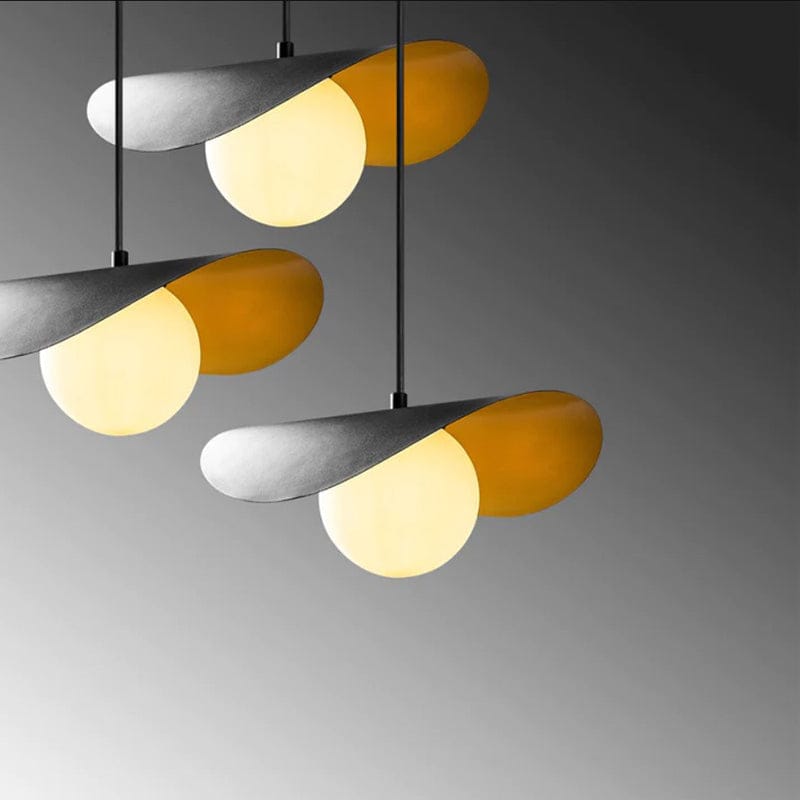 Three modern pendant lights with curved metallic shades and glowing frosted globe bulbs, arranged against a dark gray gradient background.