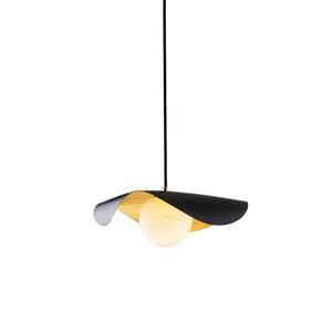 A modern pendant light with a black metal frame, a warm gold-toned inner shade, and a glowing frosted glass globe bulb, suspended by a thin black cord against a solid white background.