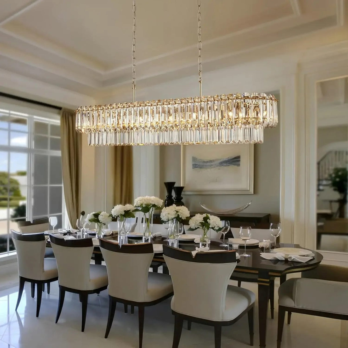 A large rectangular crystal chandelier with hanging clear glass rods and gold-toned frame details, suspended over a dining table in a bright, elegant dining room.