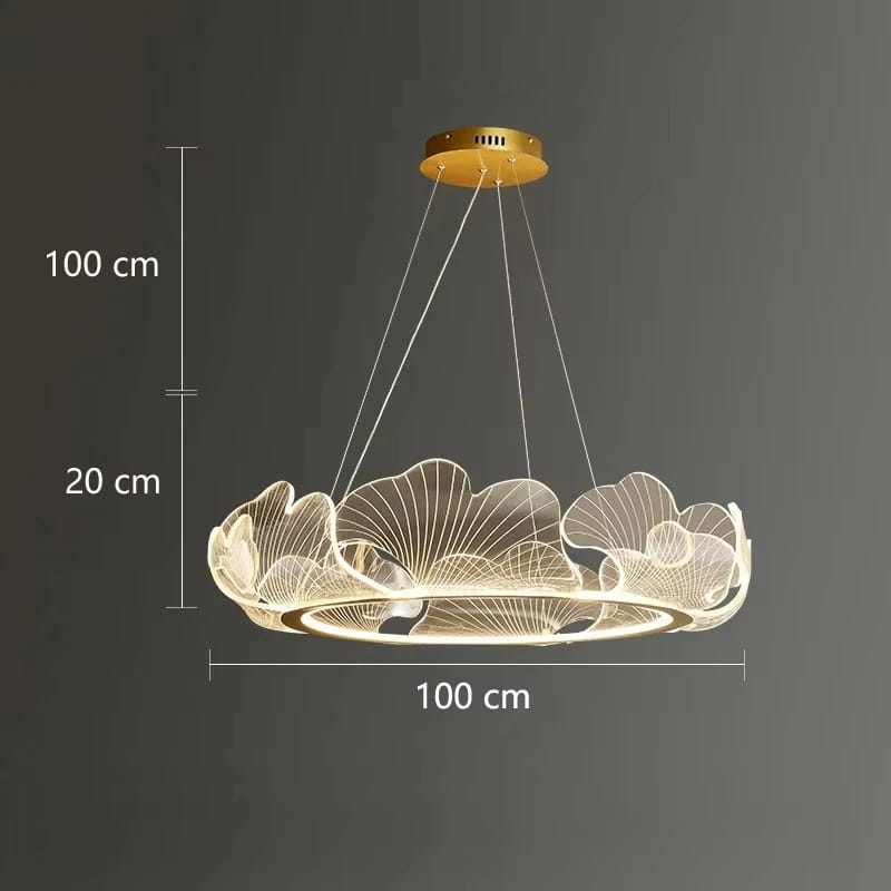 A modern LED pendant light with a gold ceiling canopy and a circular frame made of glowing wire-like leaf or petal shapes, shown against a dark gray background with dimension labels indicating 100 cm width and 100 cm plus 20 cm hanging height.