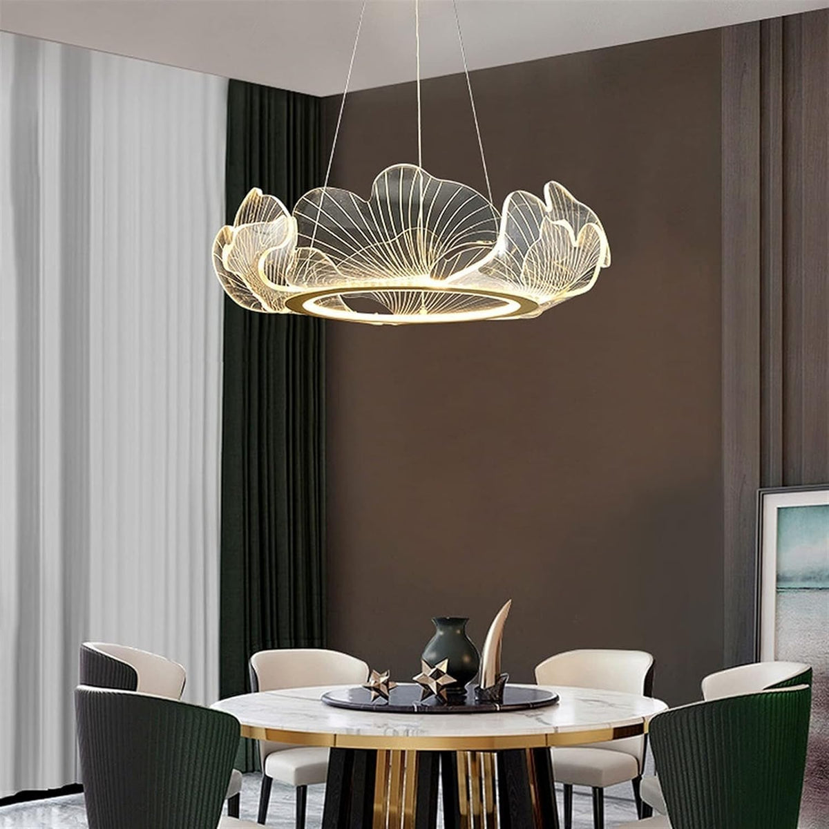 A modern flower-shaped LED pendant chandelier with a warm glowing light, suspended in a contemporary dining room setting with a round marble-top table and dark green chairs.
